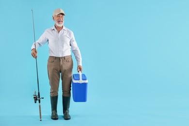 Photo of Fisherman with rod and cool box on light blue background