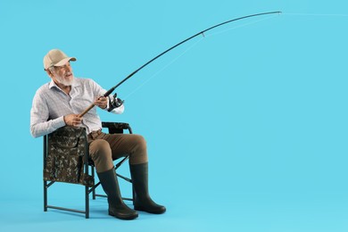 Fisherman with rod on fishing chair against light blue background