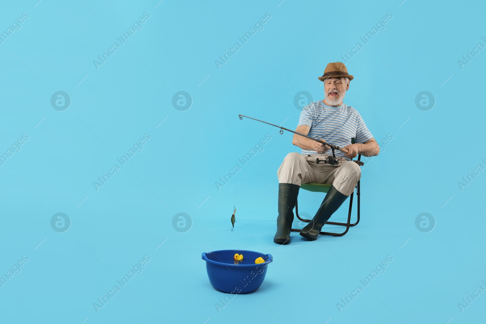 Photo of Fisherman with rod having fun against light blue background. Space for text