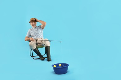 Photo of Fisherman with rod having fun against light blue background. Space for text