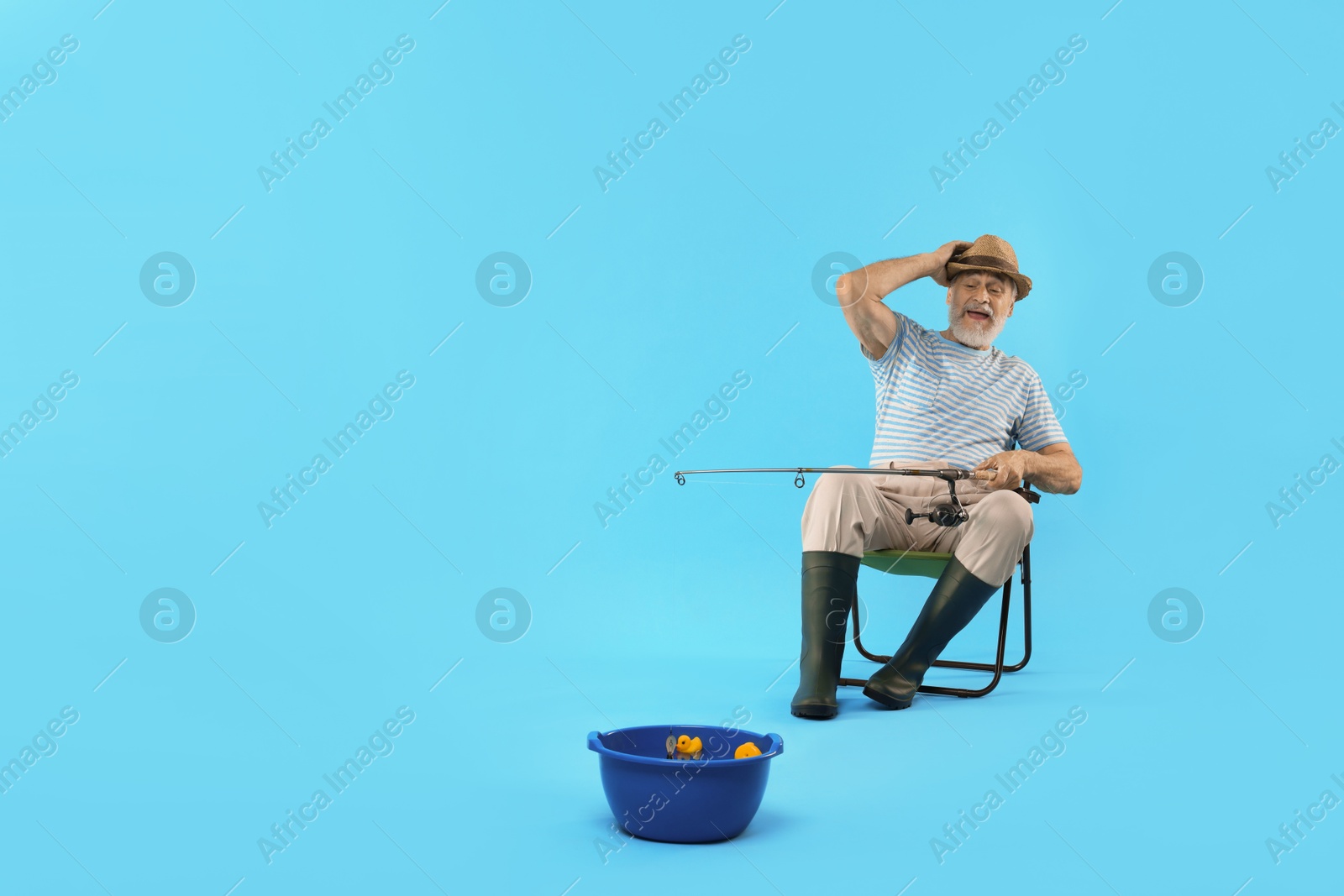 Photo of Fisherman with rod having fun against light blue background. Space for text