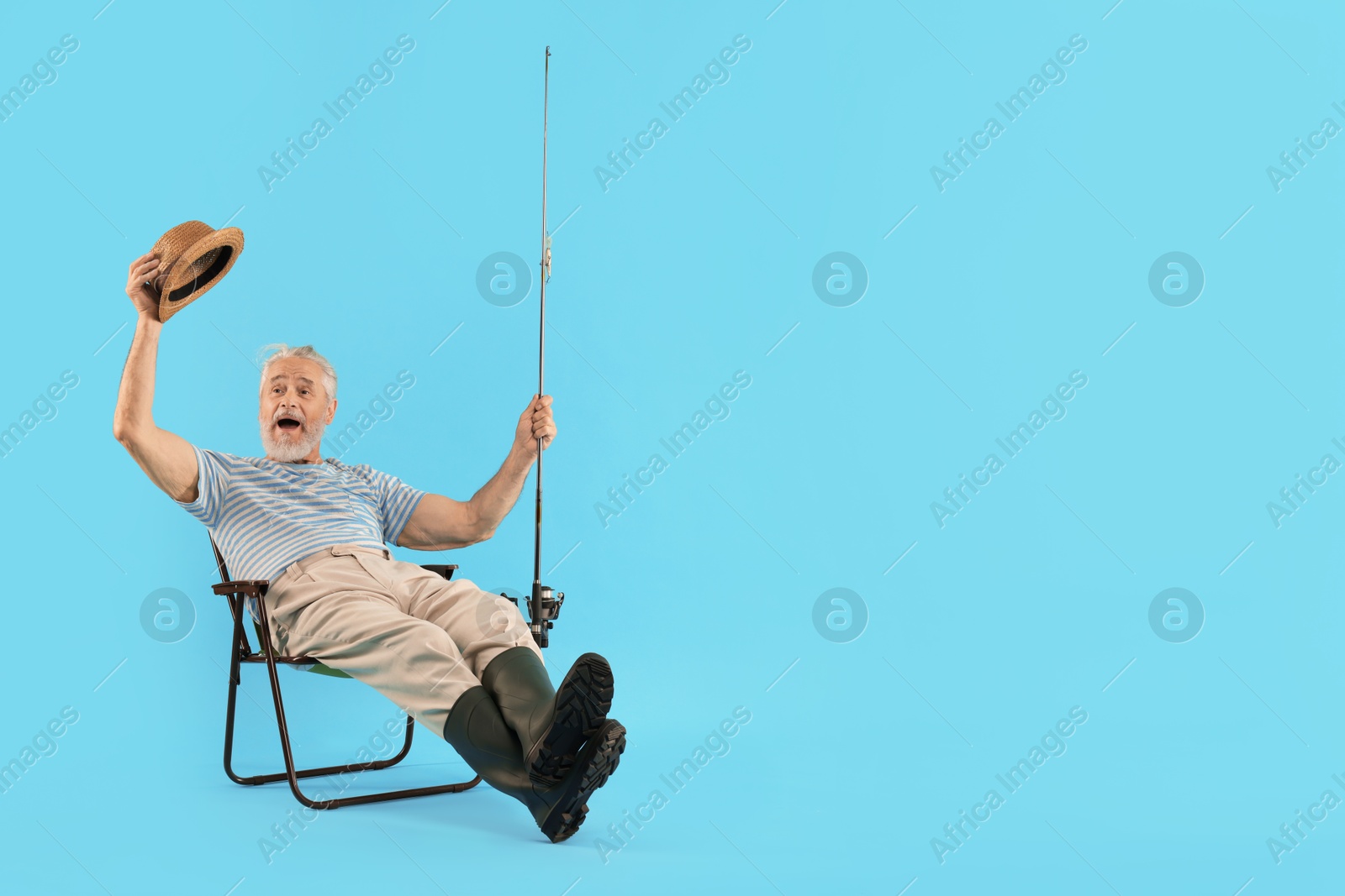 Photo of Fisherman with rod on fishing chair against light blue background. Space for text