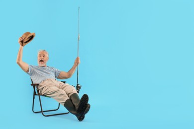 Fisherman with rod on fishing chair against light blue background. Space for text