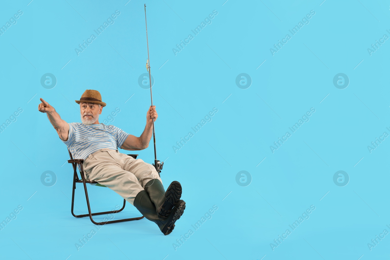 Photo of Fisherman with rod on fishing chair against light blue background. Space for text