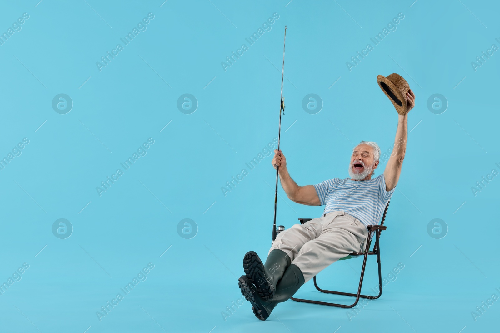 Photo of Fisherman with rod on fishing chair against light blue background. Space for text