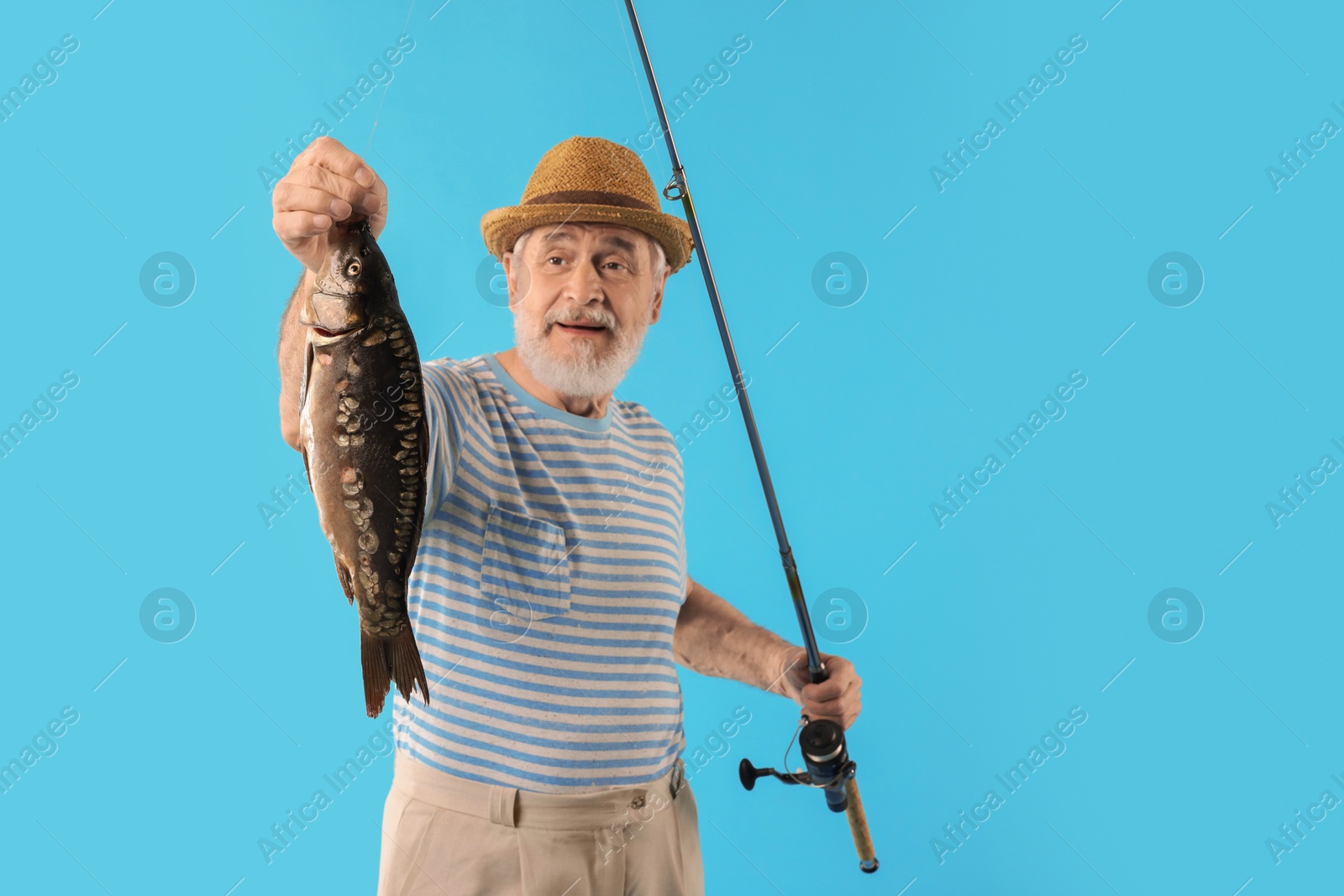 Photo of Fisherman with rod and catch on light blue background