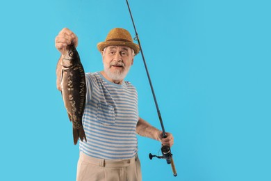 Photo of Fisherman with rod and catch on light blue background