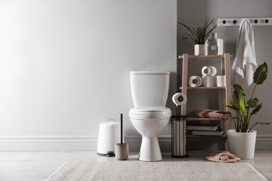 Photo of White toilet bowl, paper rolls and houseplants in bathroom, space for text