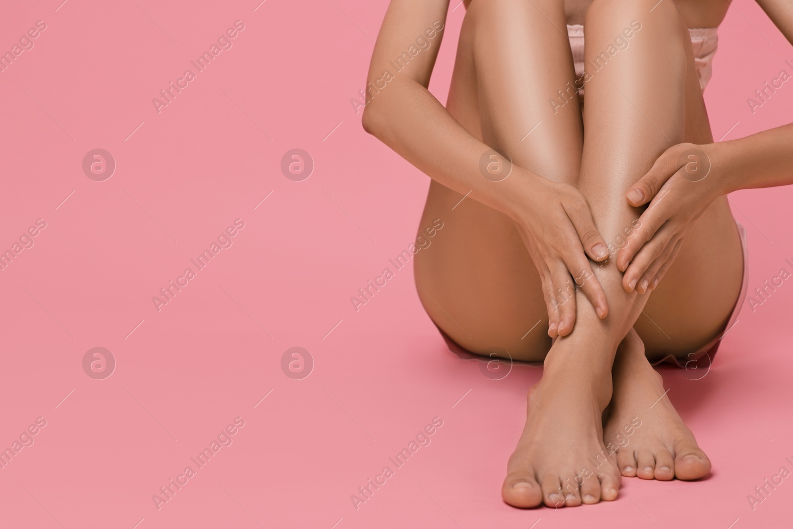 Photo of Woman touching her smooth legs on pink background, closeup. Space for text