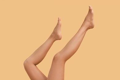 Photo of Woman with smooth legs on beige background, closeup