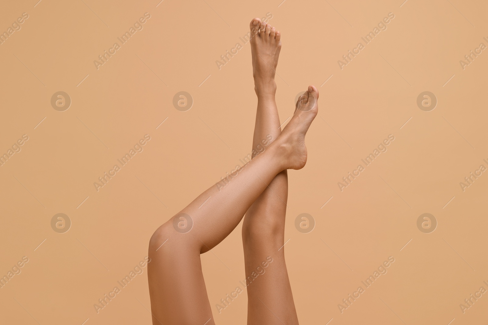 Photo of Woman with smooth legs on beige background, closeup