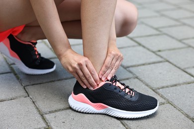 Photo of Woman suffering from foot pain outdoors, closeup