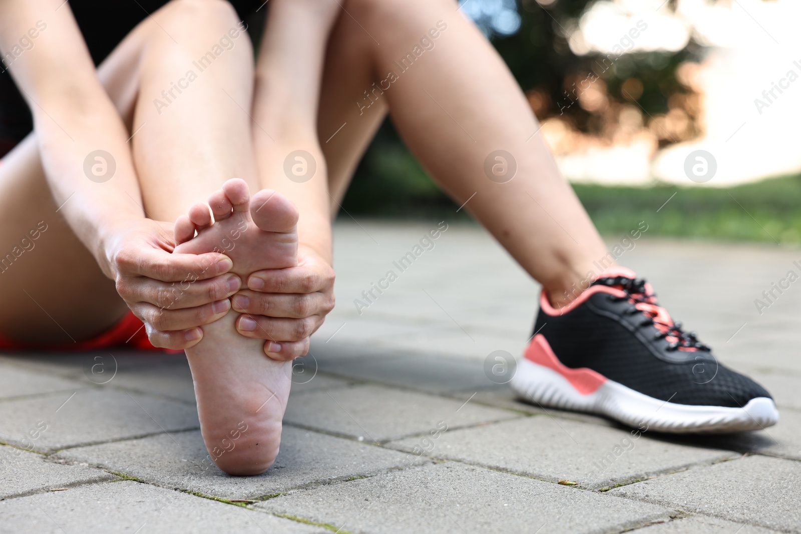 Photo of Woman suffering from foot pain outdoors, closeup