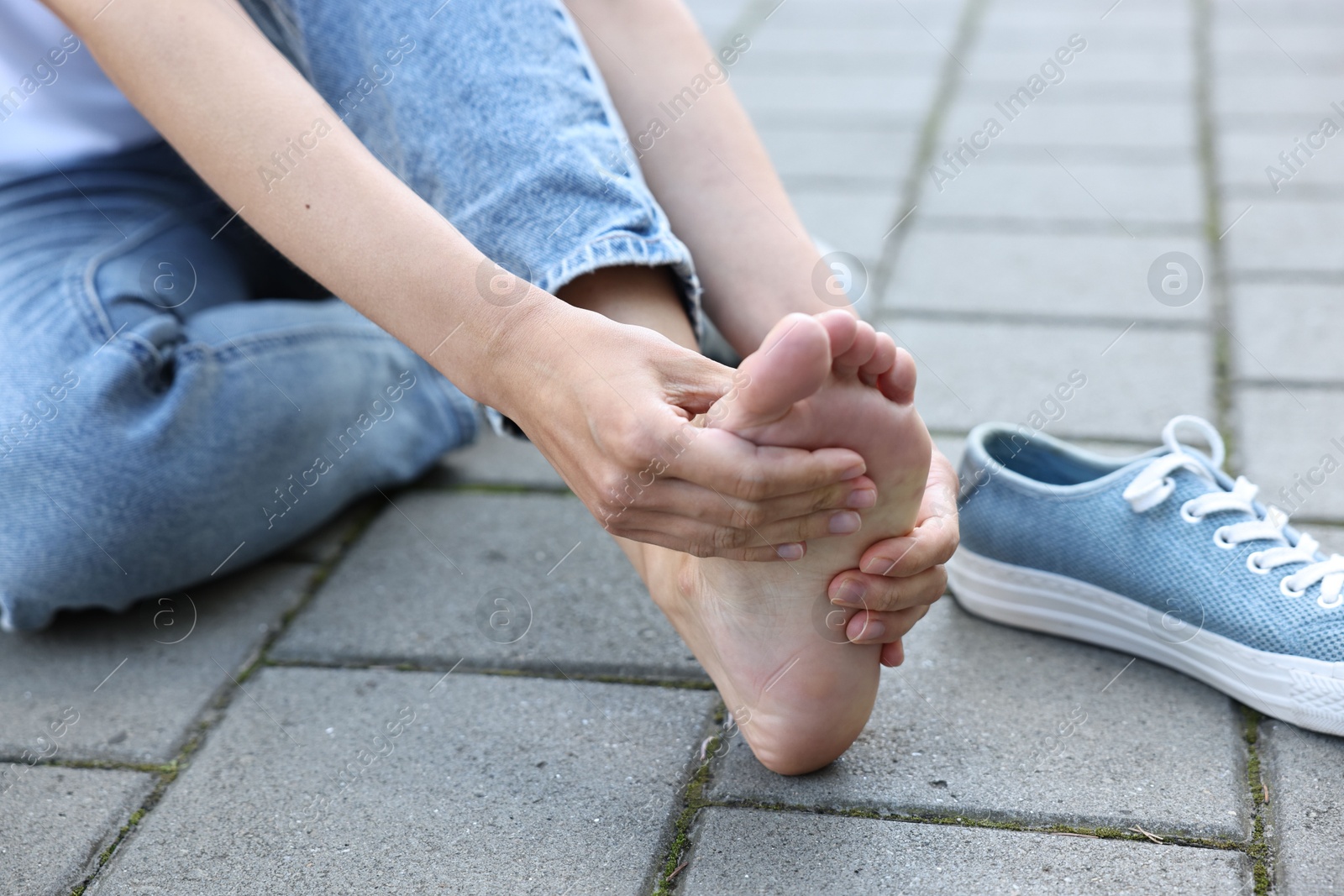 Photo of Woman suffering from foot pain outdoors, closeup