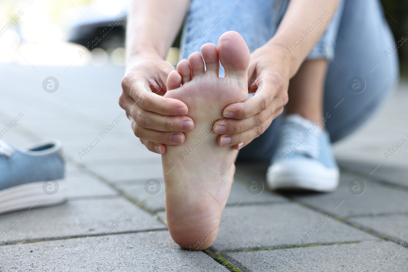 Photo of Woman suffering from foot pain outdoors, closeup