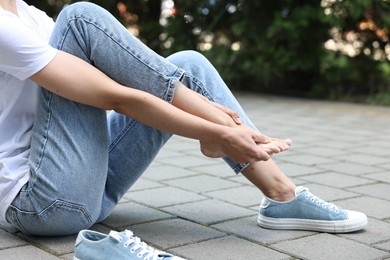 Photo of Woman suffering from foot pain outdoors, closeup