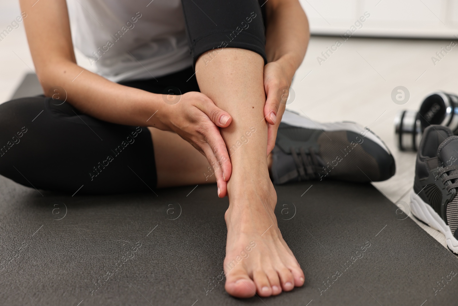 Photo of Woman suffering from foot pain at home, closeup