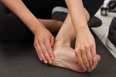 Photo of Woman suffering from foot pain at home, closeup