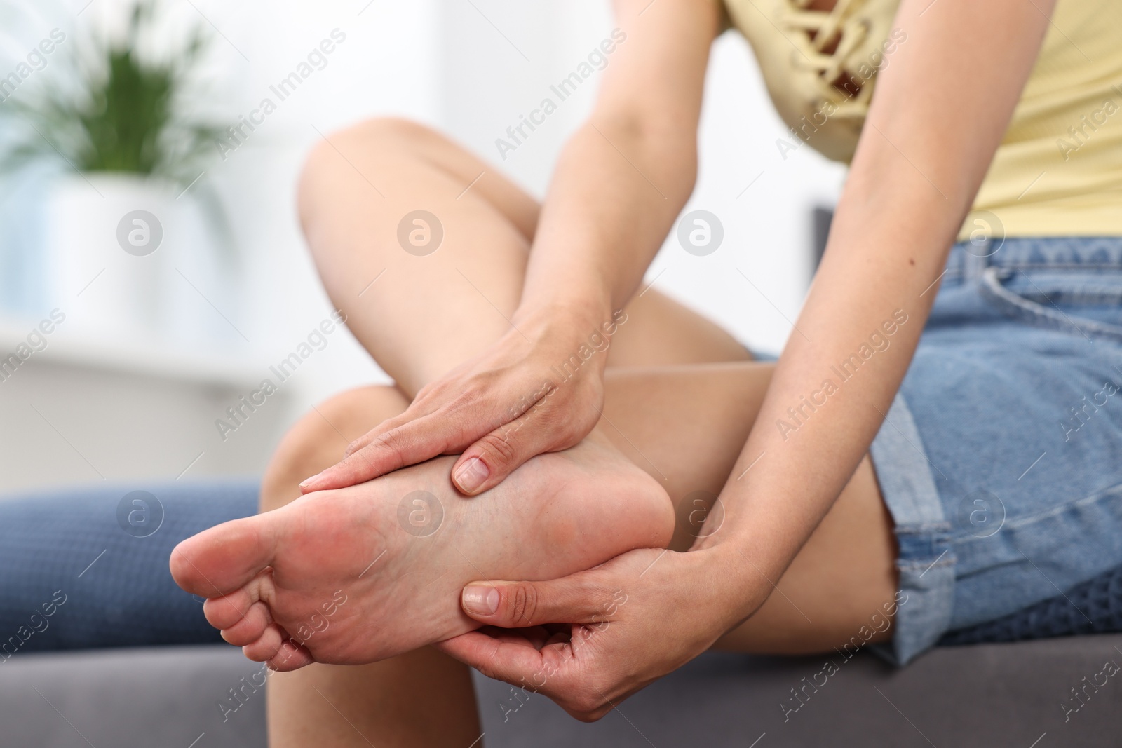 Photo of Woman suffering from foot pain on bed at home, closeup