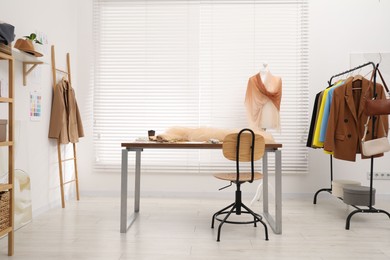 Photo of Fashion designer`s workplace with fashionable clothes, fabric samples and sewing supplies