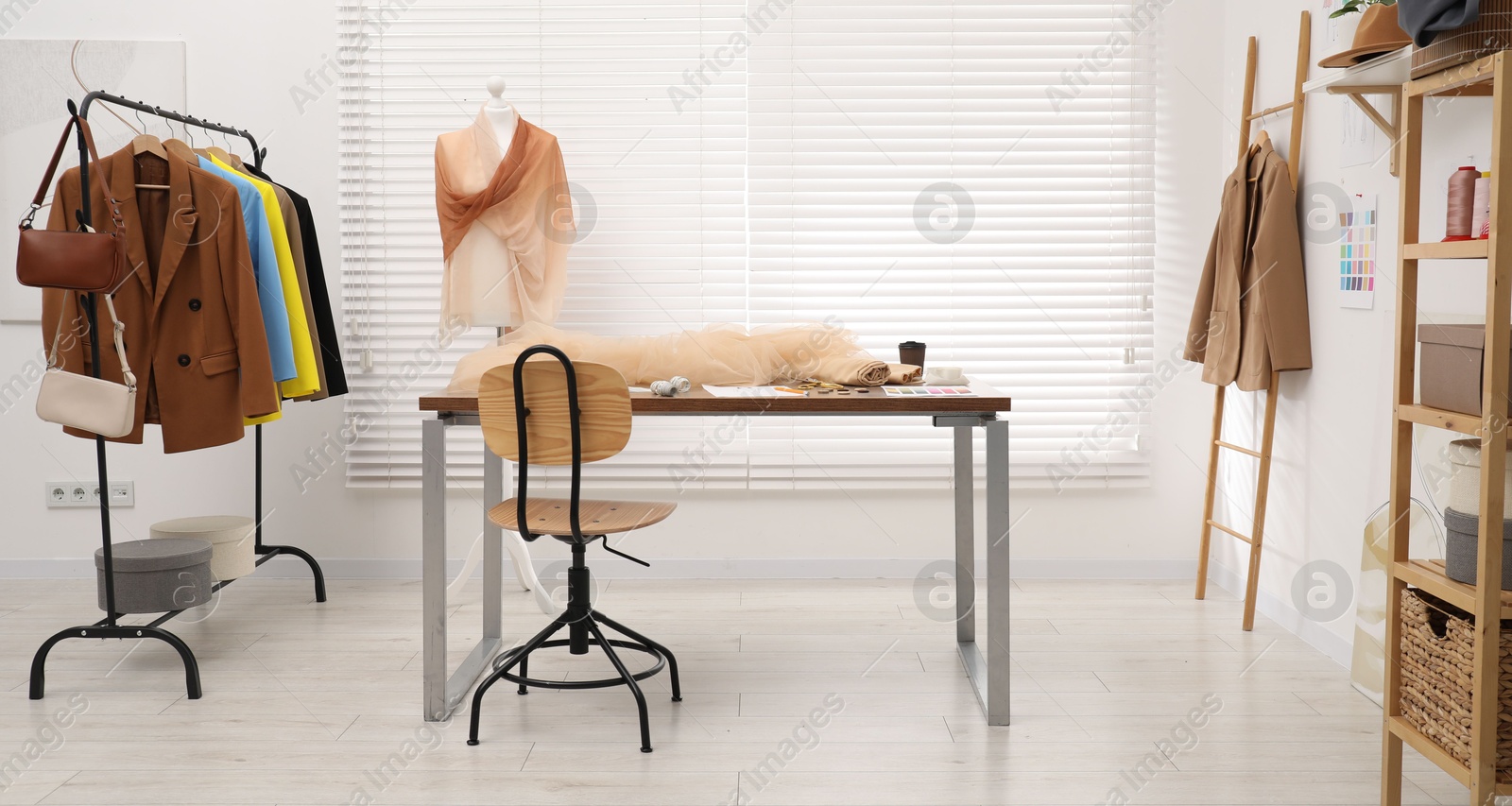 Photo of Fashion designer`s workplace with fashionable clothes, fabric samples and sewing supplies