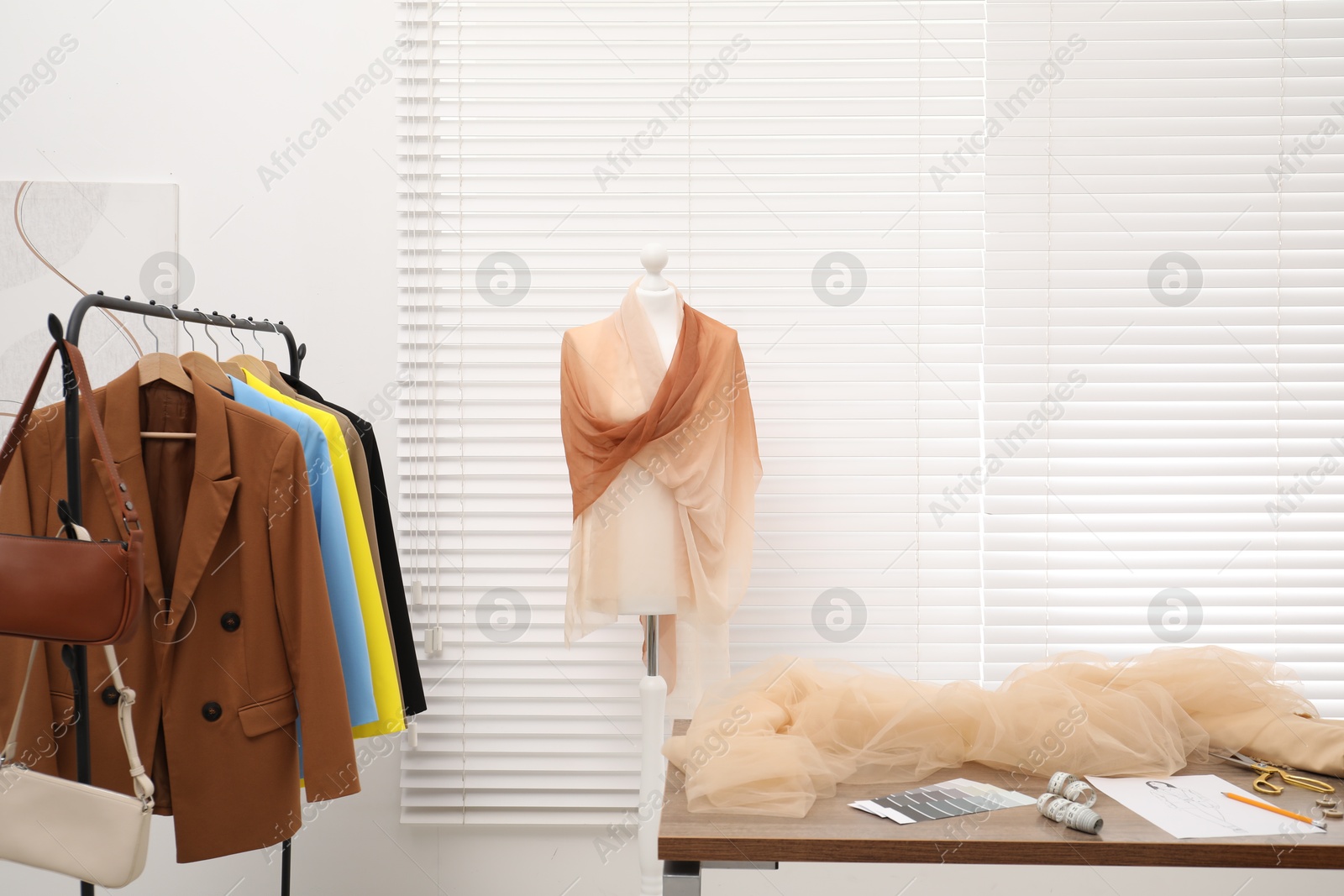 Photo of Fashion designer`s workplace with fashionable clothes, fabric samples and sewing supplies