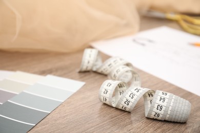 Photo of Color palette and other fashion designer`s supplies on wooden table, closeup