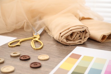 Photo of Color palette and other fashion designer`s supplies on wooden table, closeup