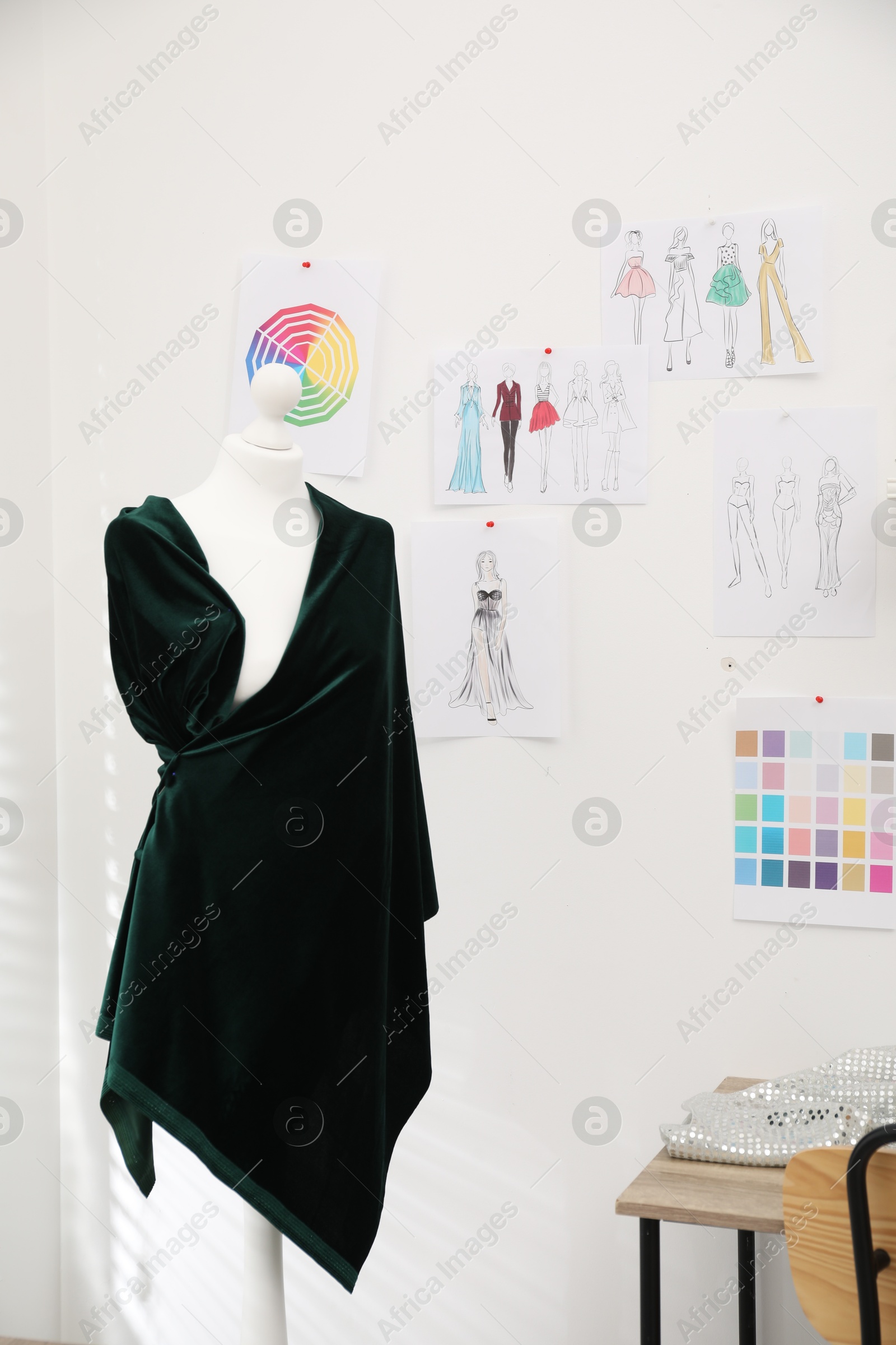 Photo of Fashion designer`s workplace with mannequin, sketches of new outfits and other supplies