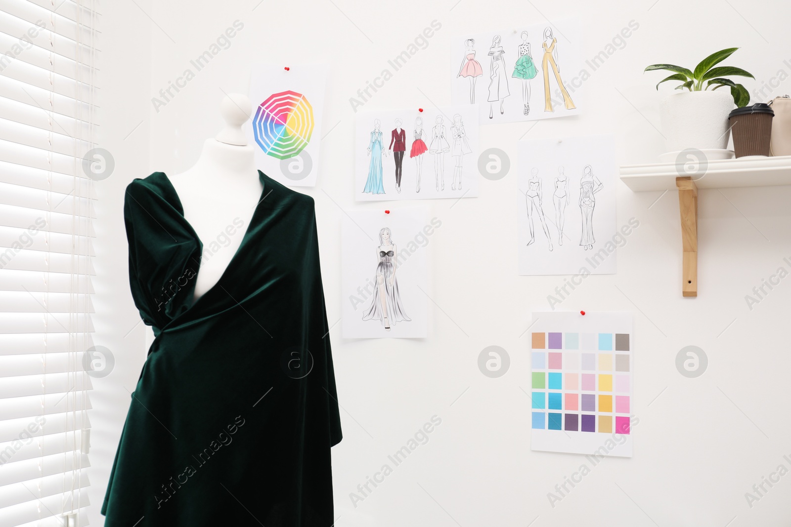 Photo of Fashion designer`s workplace with mannequin, sketches of new outfits and other supplies