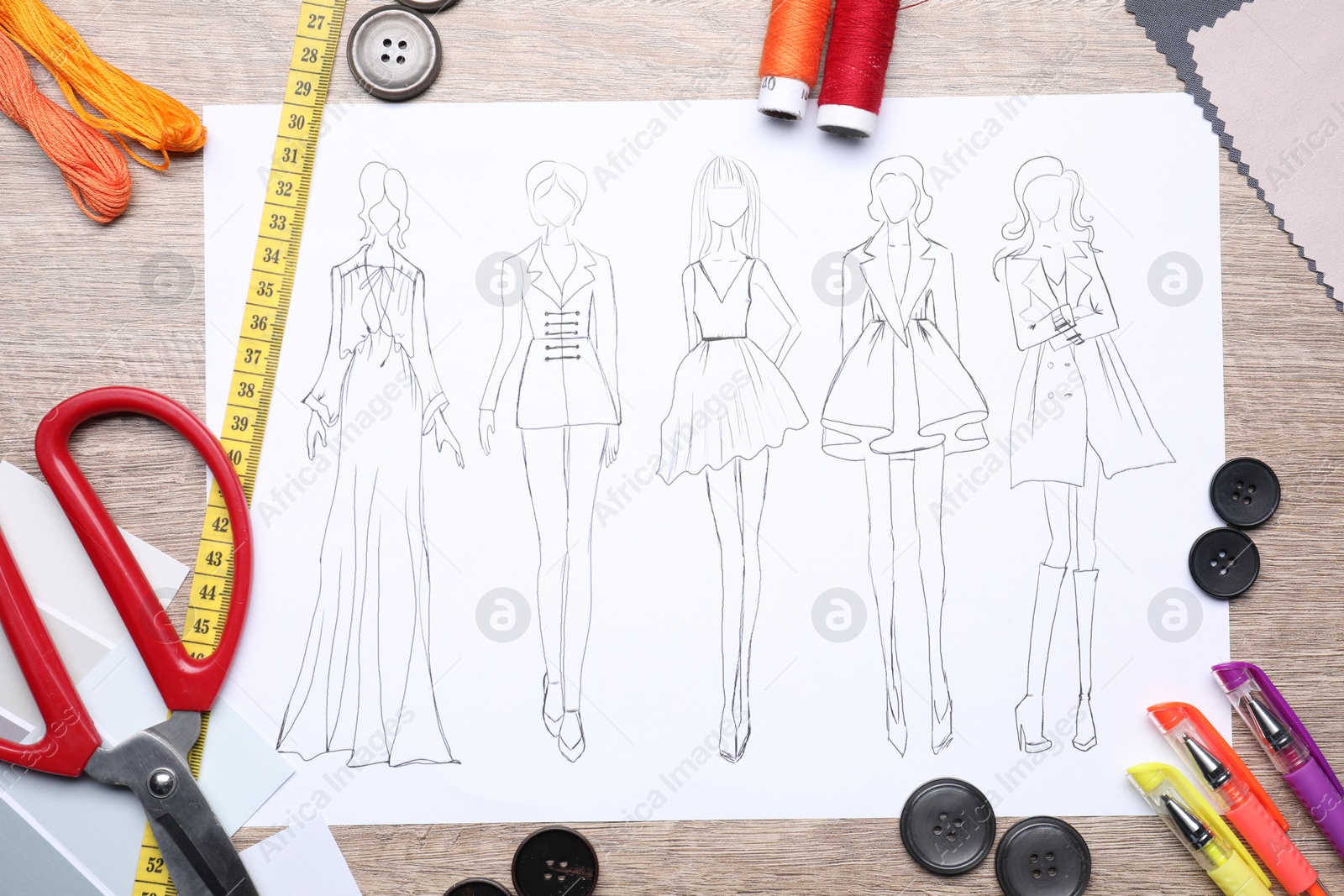 Photo of Sketch of stylish clothes and other fashion designer`s supplies on wooden table, flat lay