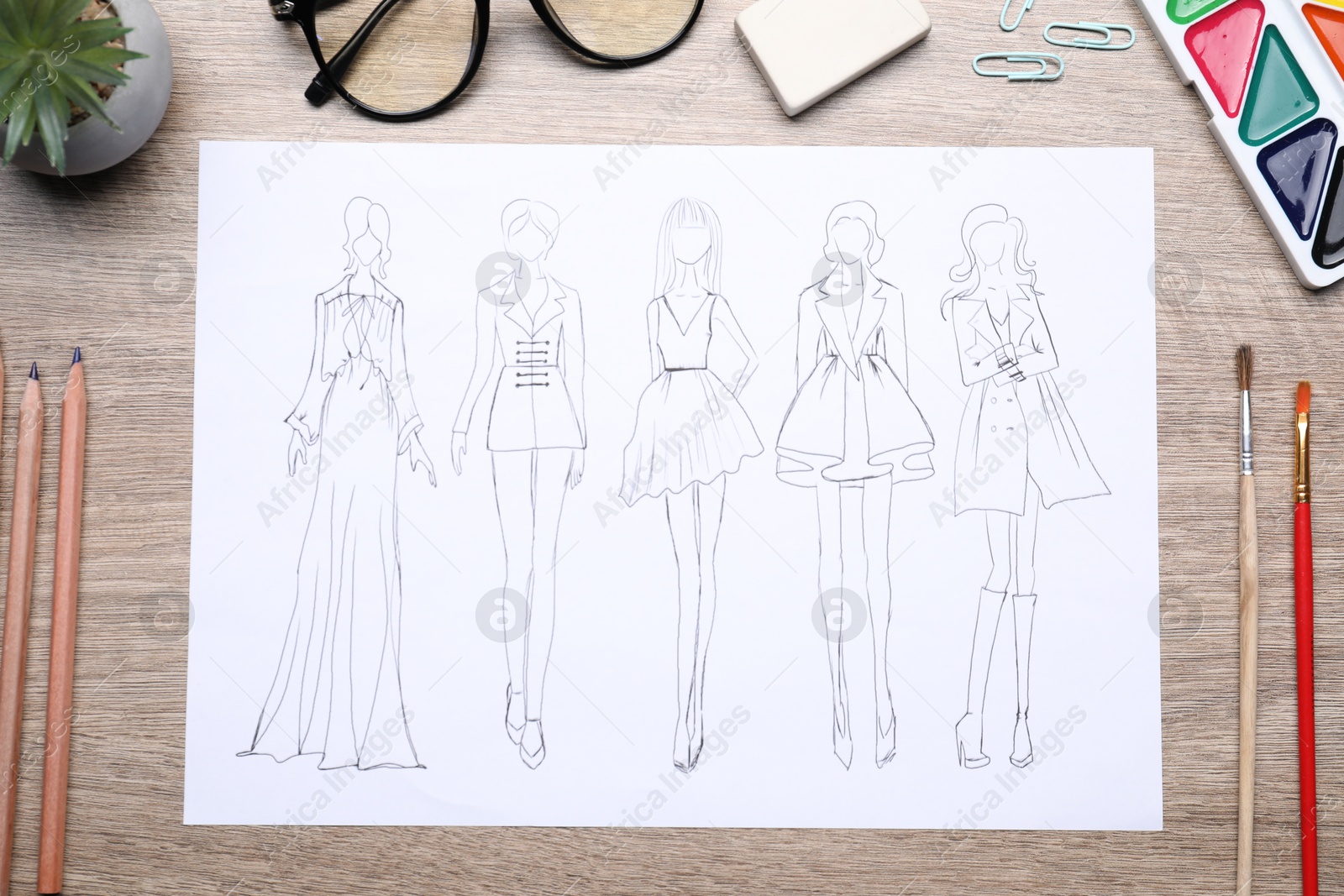 Photo of Sketch of stylish clothes and other fashion designer`s supplies on wooden table, flat lay