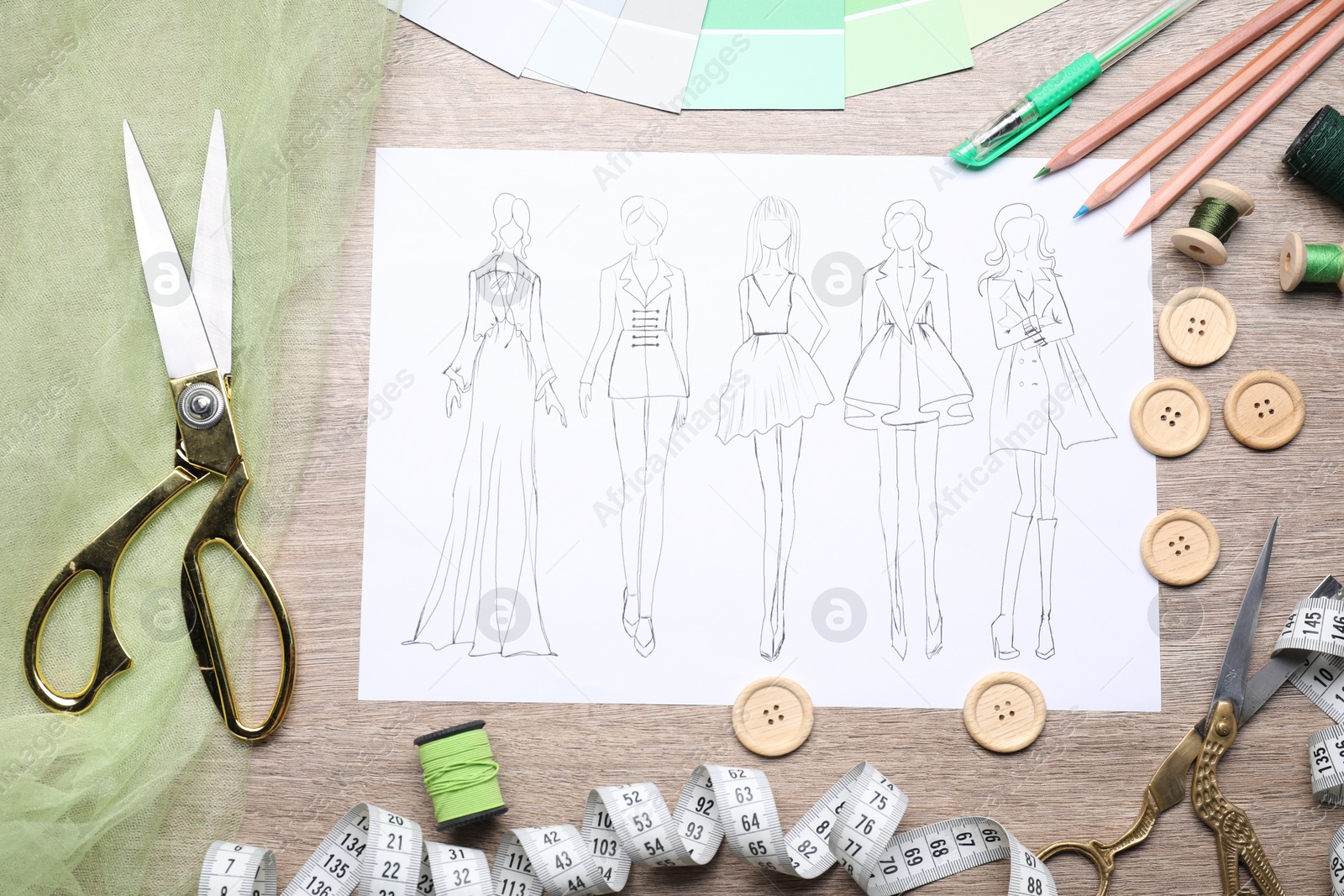 Photo of Sketch of stylish clothes and other fashion designer`s supplies on wooden table, flat lay