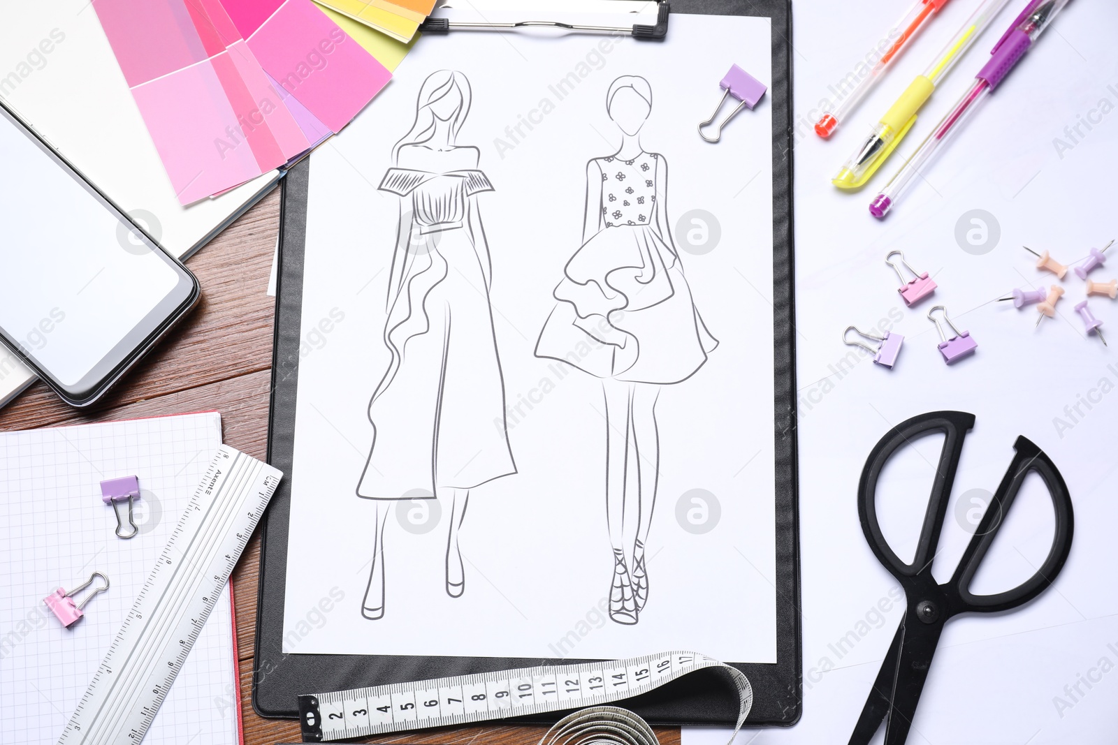 Photo of Sketch of stylish clothes and other fashion designer`s supplies on wooden table, flat lay