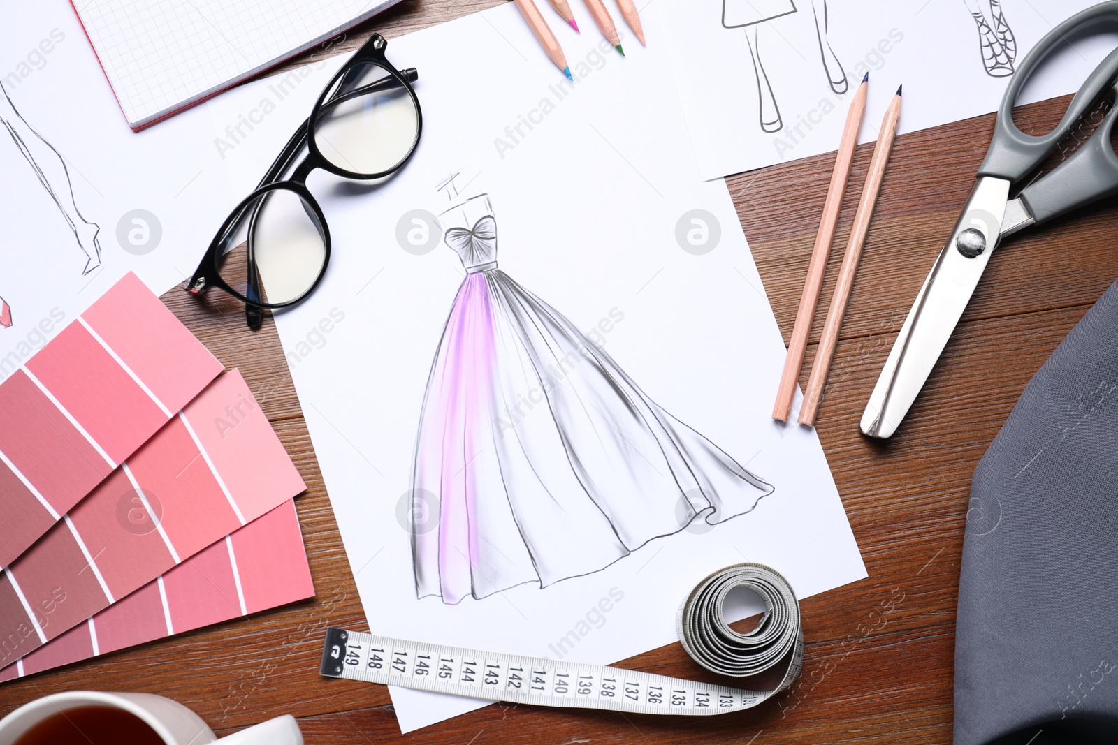 Photo of Sketches of stylish clothes and other fashion designer`s supplies on wooden table, flat lay