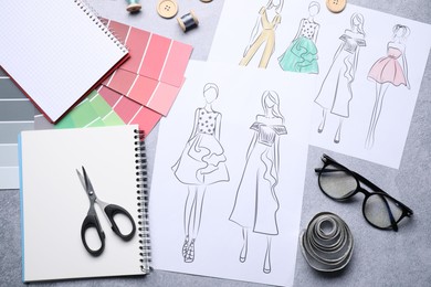 Photo of Sketches of stylish clothes and other fashion designer`s supplies on grey table, flat lay