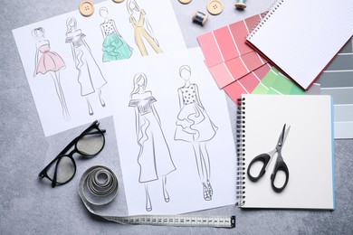 Photo of Sketches of stylish clothes and other fashion designer`s supplies on grey table, flat lay