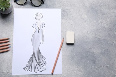 Photo of Sketch of stylish clothes and other fashion designer`s supplies on grey table, flat lay. Space for text