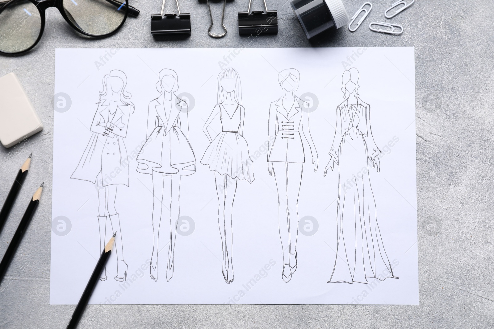 Photo of Sketch of stylish clothes and other fashion designer`s supplies on grey table, flat lay