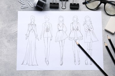 Photo of Sketch of stylish clothes and other fashion designer`s supplies on grey table, flat lay