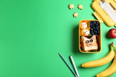 Photo of Lunch box with snacks, pen and pencil on green table, flat lay. Space for text