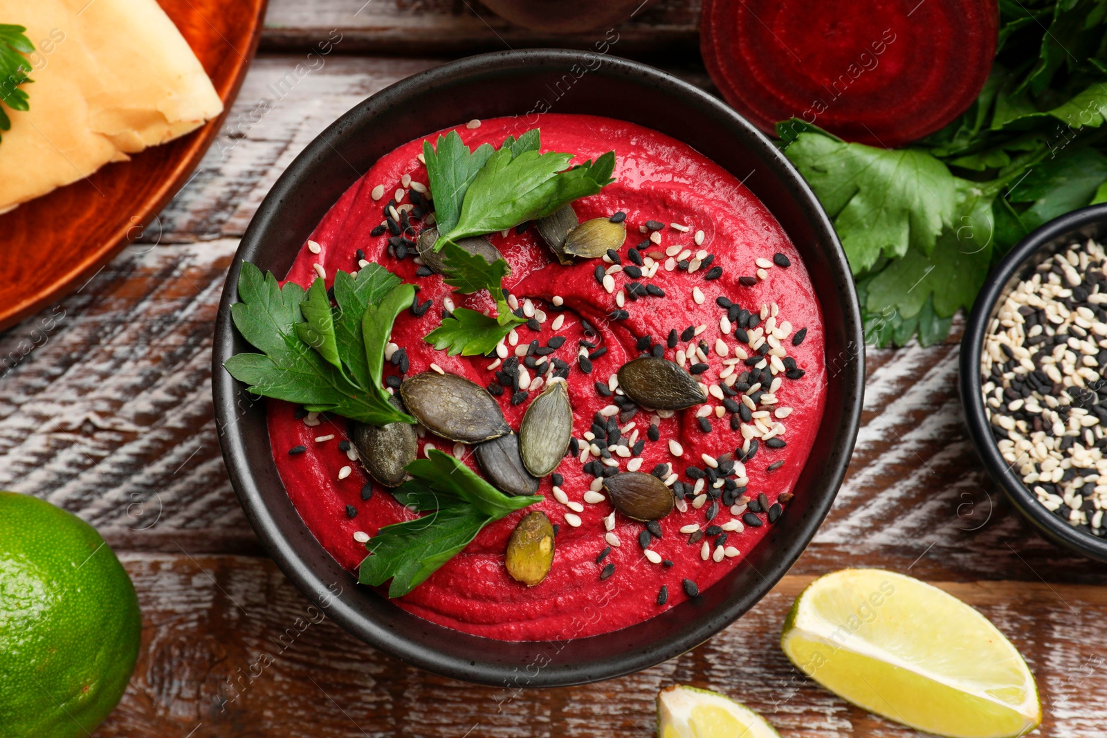 Photo of Tasty beetroot hummus in bowl and products on wooden table, flat lay