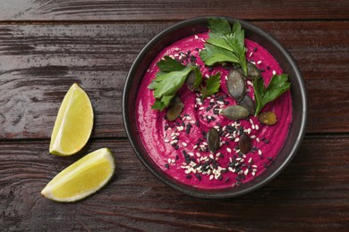 Tasty beetroot hummus in bowl on wooden table, top view