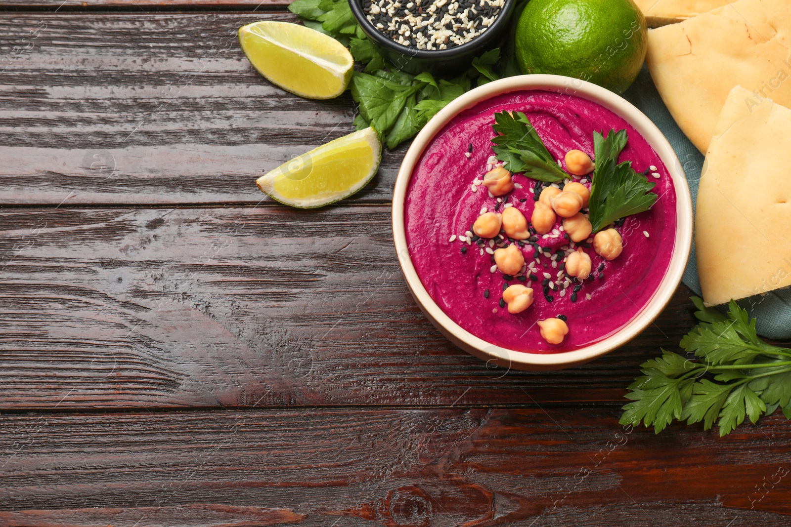 Photo of Tasty beetroot hummus in bowl and products on wooden table, flat lay. Space for text