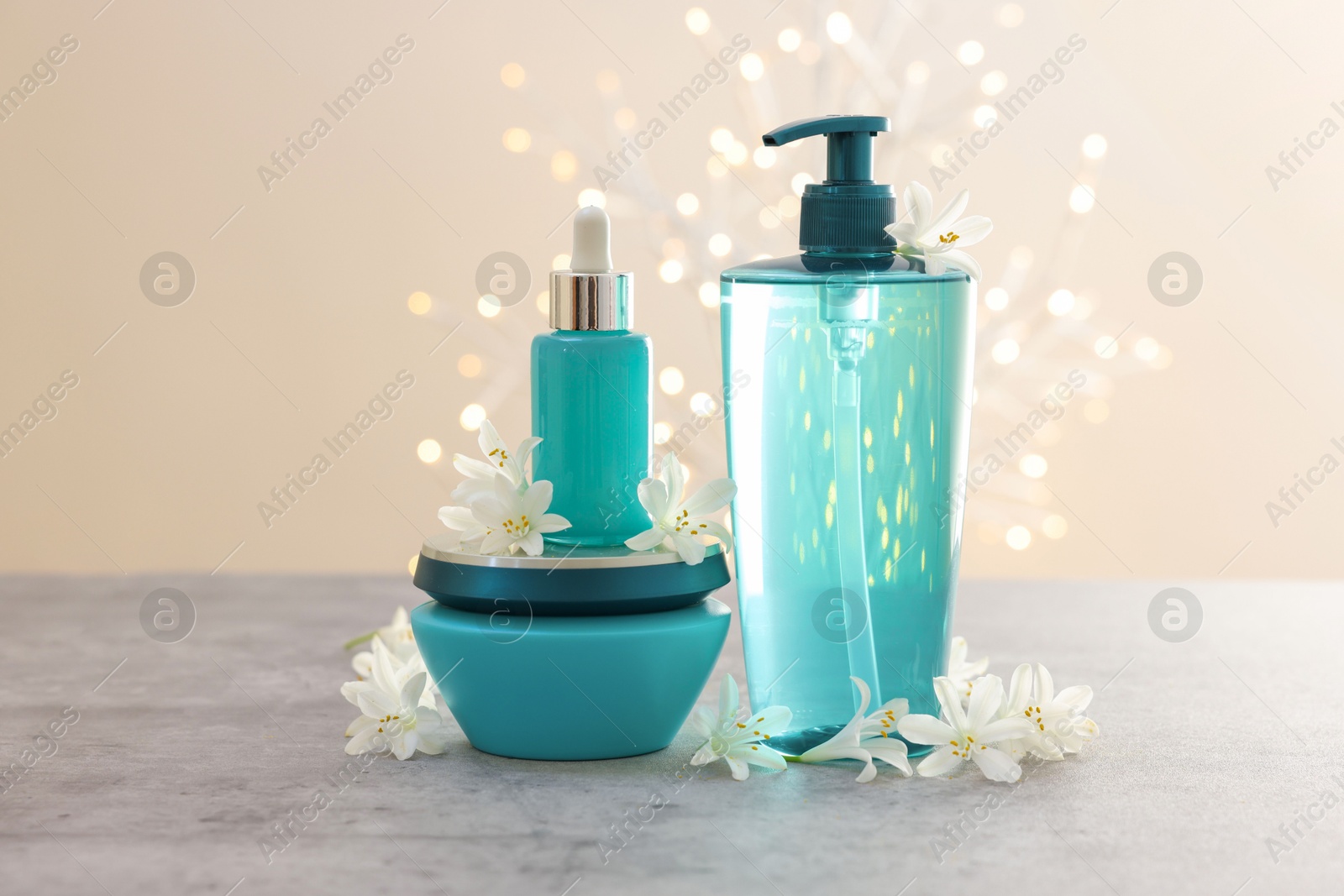 Photo of Cosmetic products and beautiful jasmine flowers on grey table