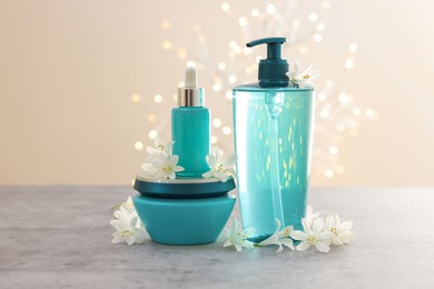 Photo of Cosmetic products and beautiful jasmine flowers on grey table