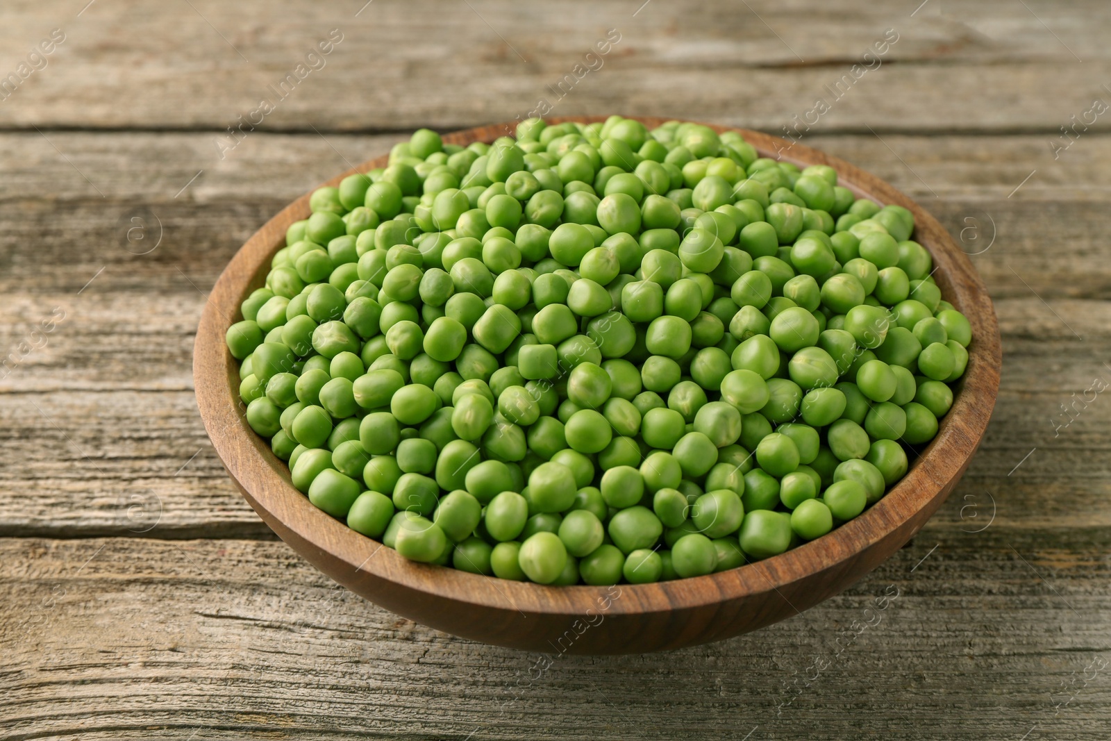 Photo of Fresh green peas in bowl on wooden table, closeup