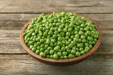 Fresh green peas in bowl on wooden table, closeup