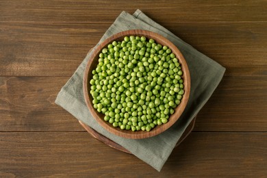 Photo of Fresh green peas in bowl on wooden table, top view