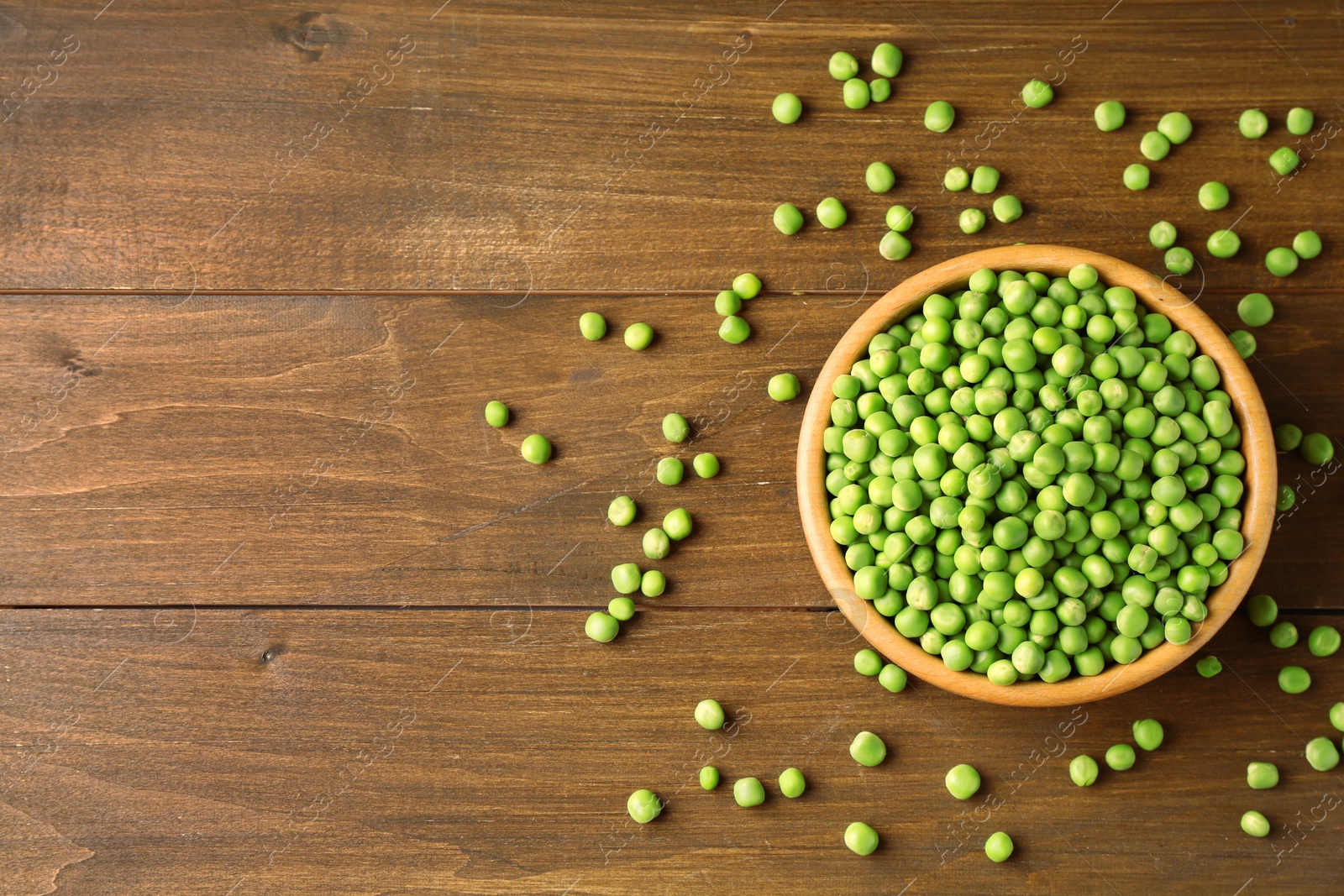 Photo of Fresh green peas in bowl on wooden table, top view. Space for text